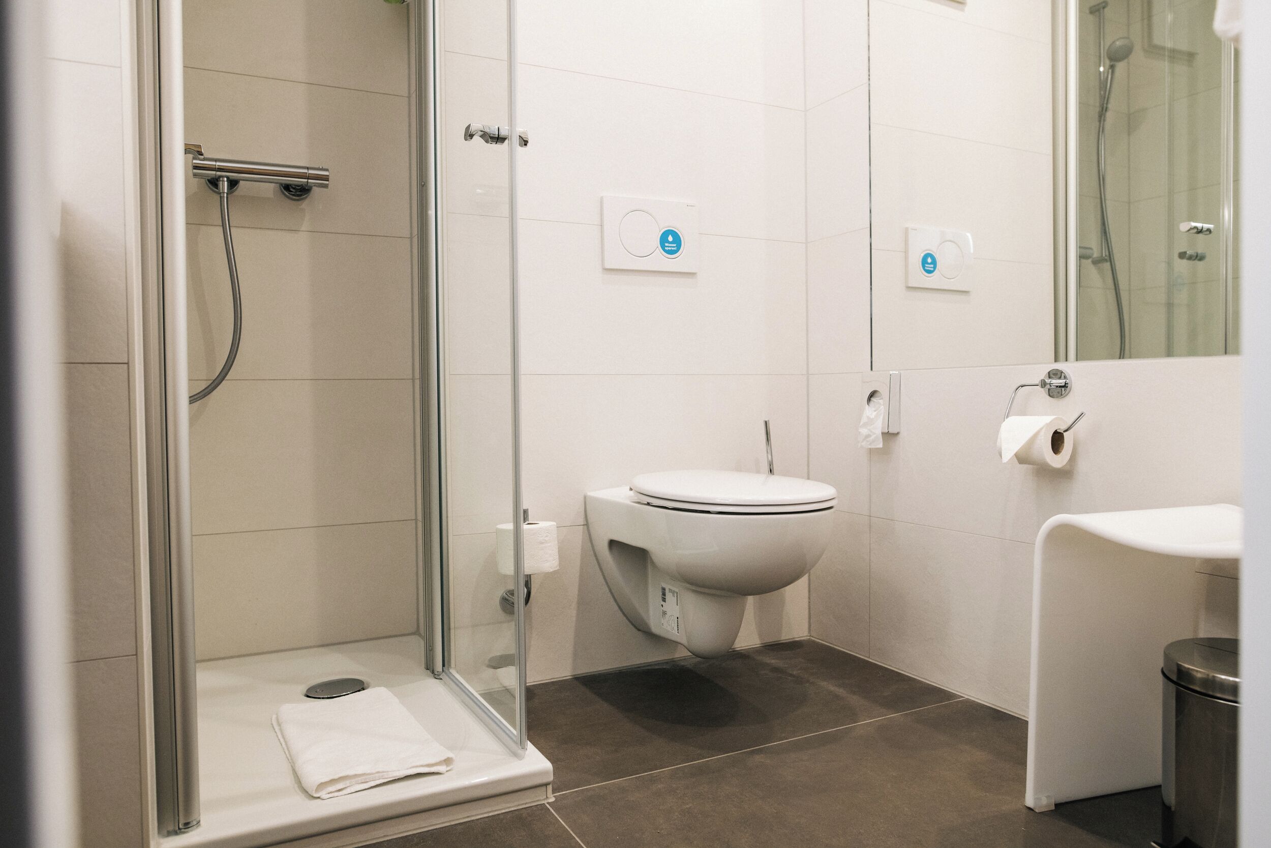 A modern bathroom with a glass-enclosed shower, a toilet, and a sink.
