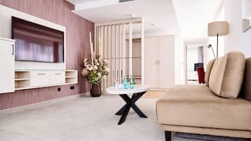 A modern living room with a flat-screen TV, a round coffee table, and a beige sofa.