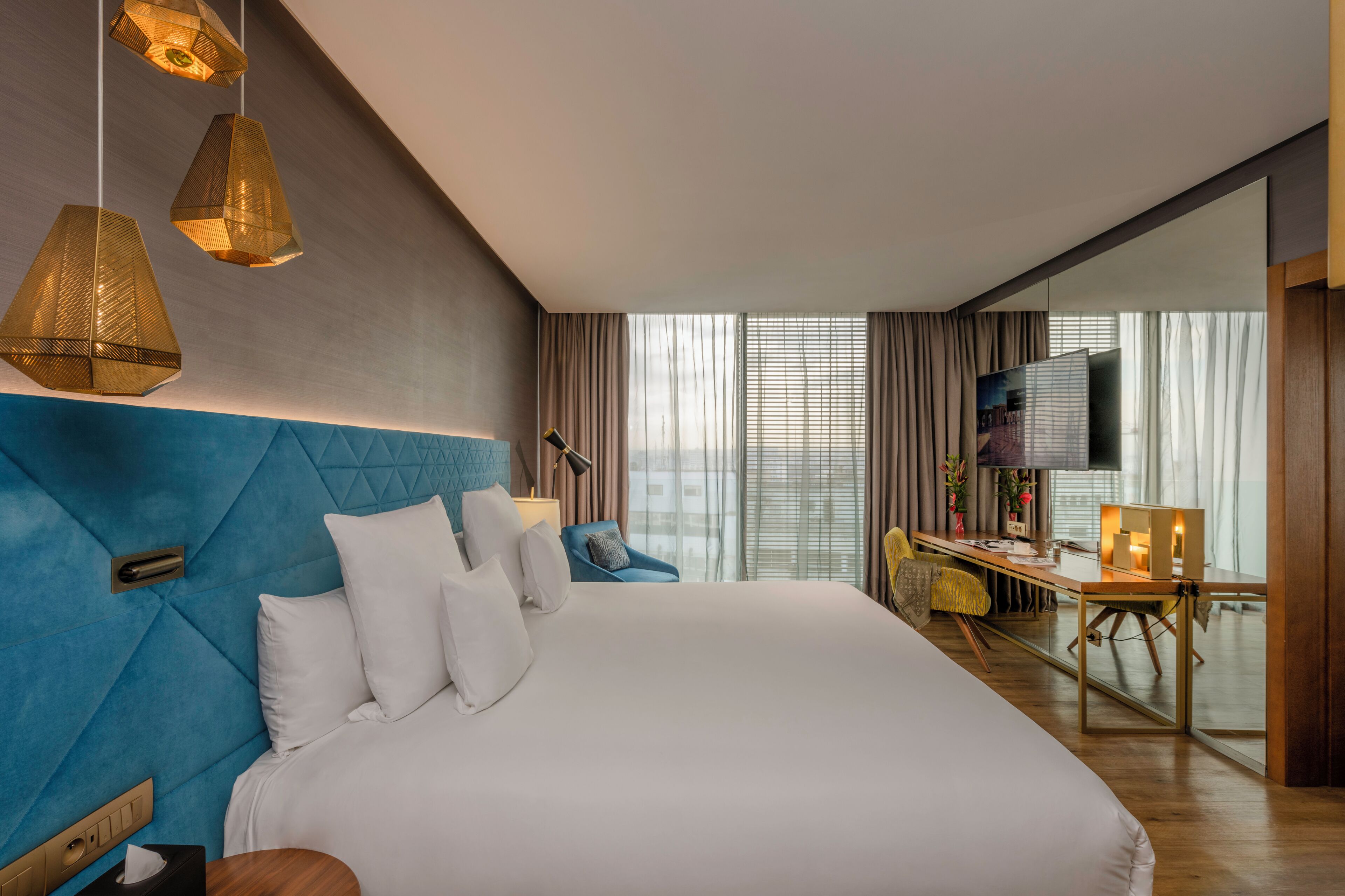 Ein modernes Hotelzimmer mit einem großen Bett, einem Schreibtisch und einem Fernseher.