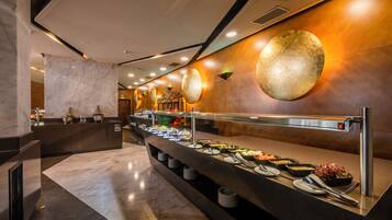 Zona de bufé con mostrador de mármol, diferentes platos de comida y una pared moderna con detalles decorativos circulares.