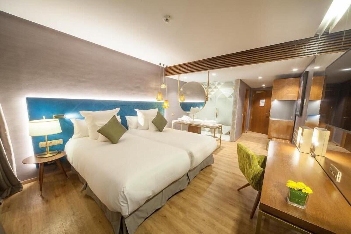 Una habitación de hotel moderna con una cama grande, mesitas de noche, un escritorio y un espejo.
