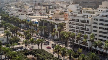 Un paysage urbain avec des bâtiments modernes, des palmiers et une rue animée.