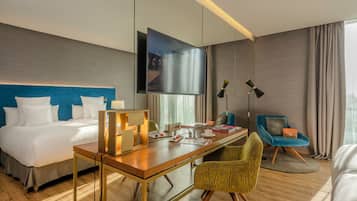 A hotel room with a bed, desk, chair, TV, and curtains.