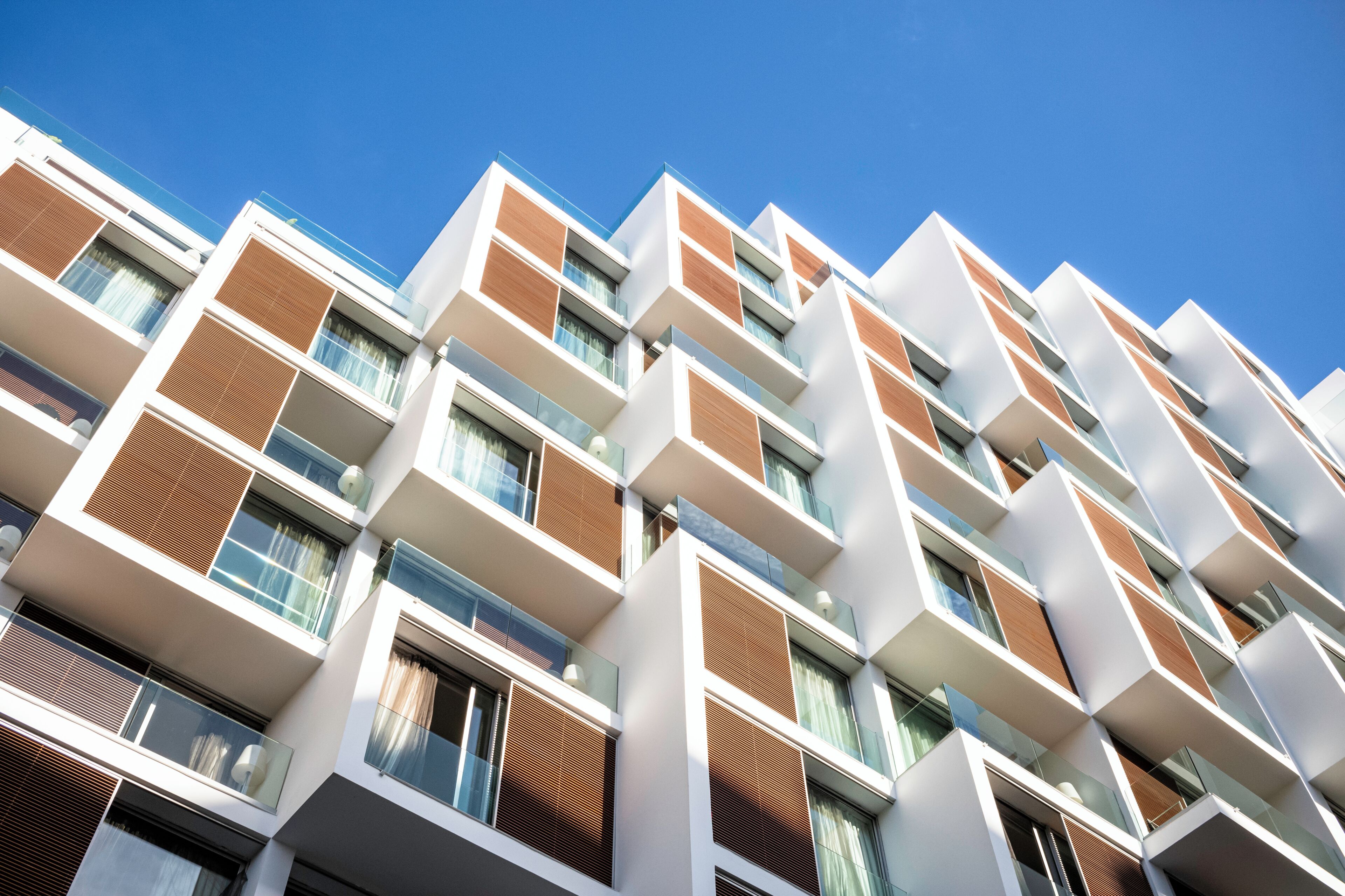 A multi-story building with a modern architectural design, featuring balconies and large windows.