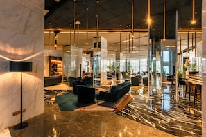 Eine moderne Lobby mit Marmorböden, einer Couch, Sesseln und einer Bar.