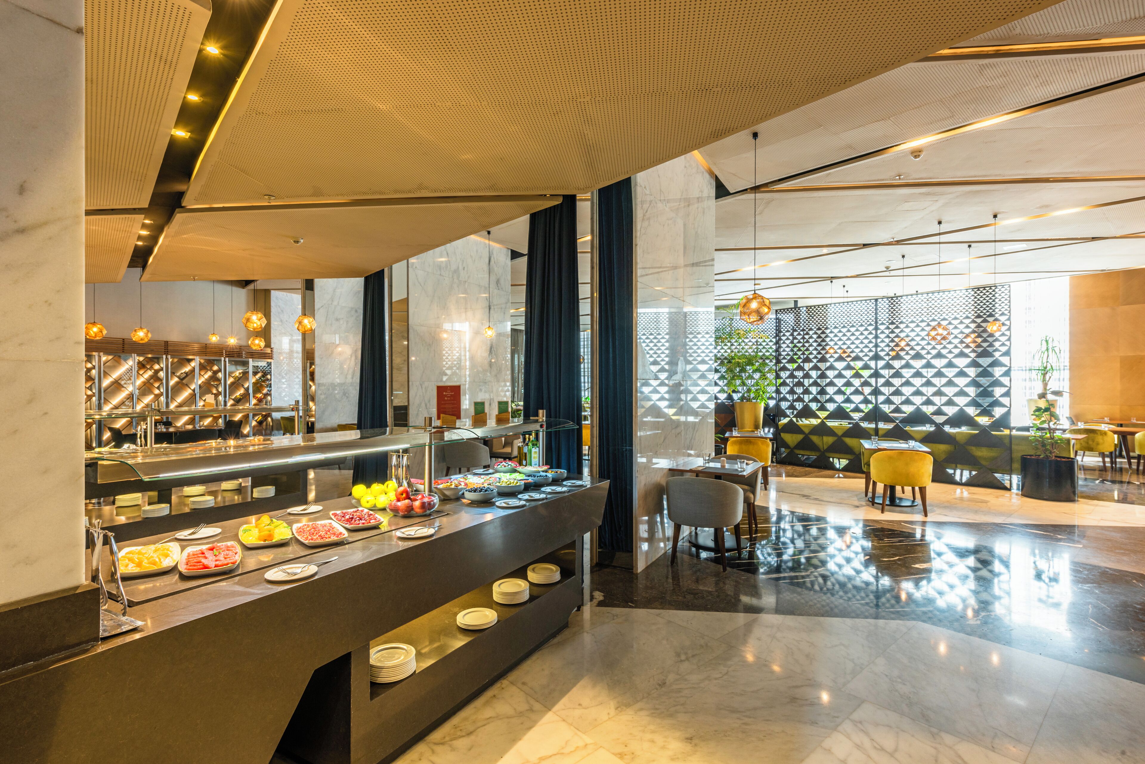 A modern hotel lobby with a buffet area, marble flooring, and contemporary furniture.