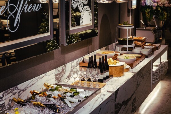 A buffet setup with various food items, wine bottles, and glasses on a marble counter. - Kensington Hotel Yeouido Seoul (Seoul)
