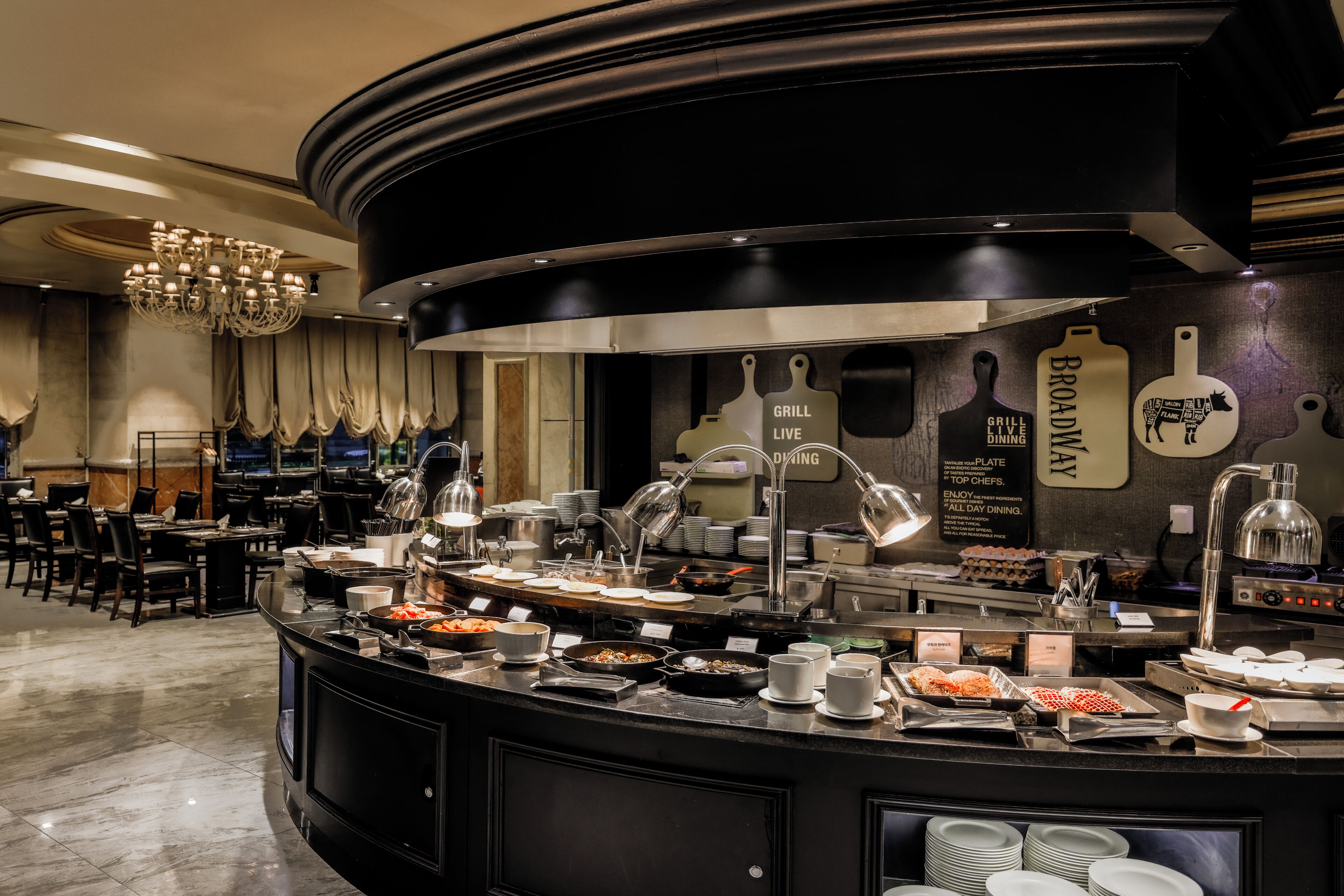 A buffet area with various food stations, a chandelier, and a wall with kitchen utensils.