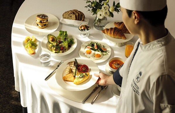 A table set with various breakfast dishes, a chef, and a glass of orange juice. - Kensington Hotel Yeouido Seoul (Seoul)