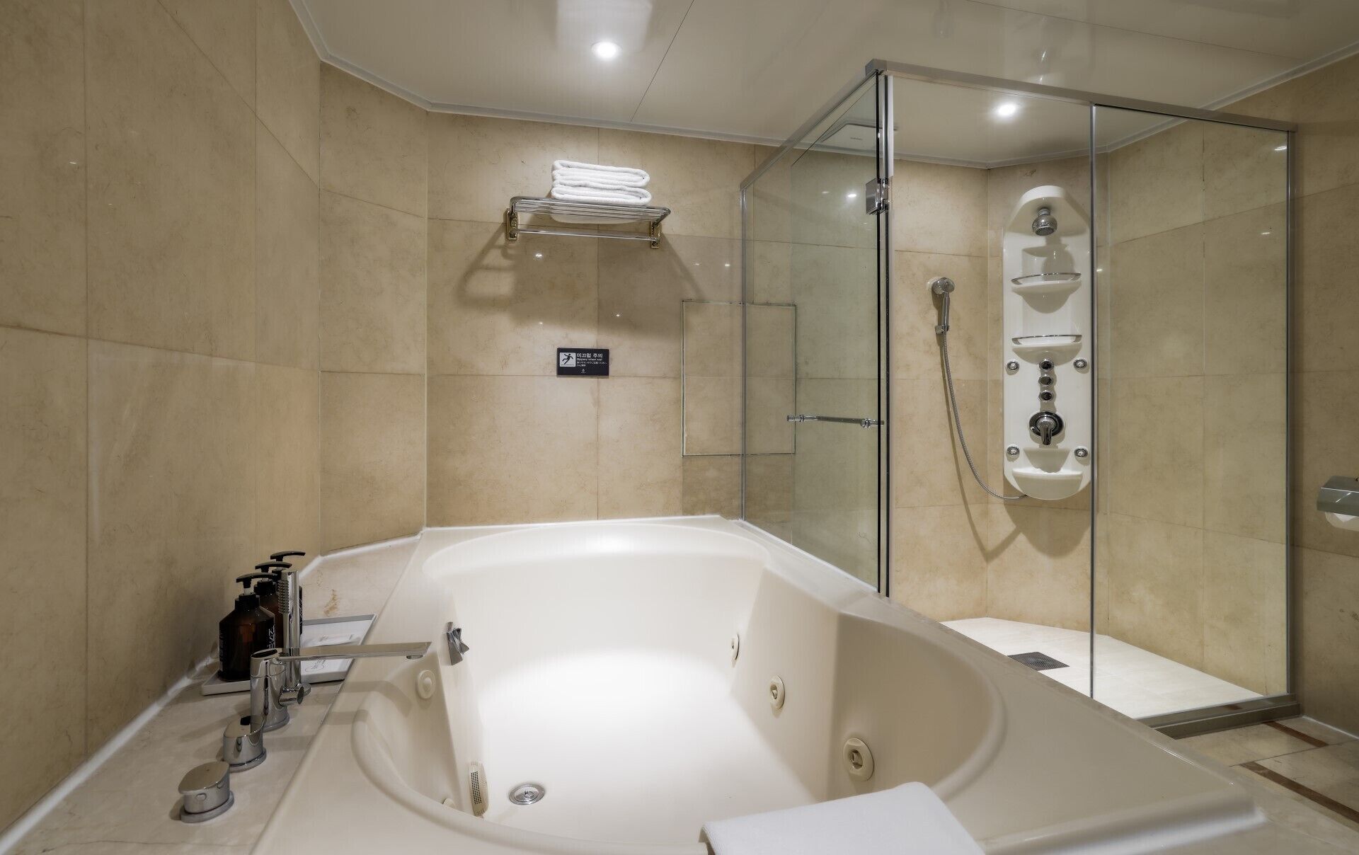 A modern bathroom with a large bathtub, a glass-enclosed shower, and a towel rack.