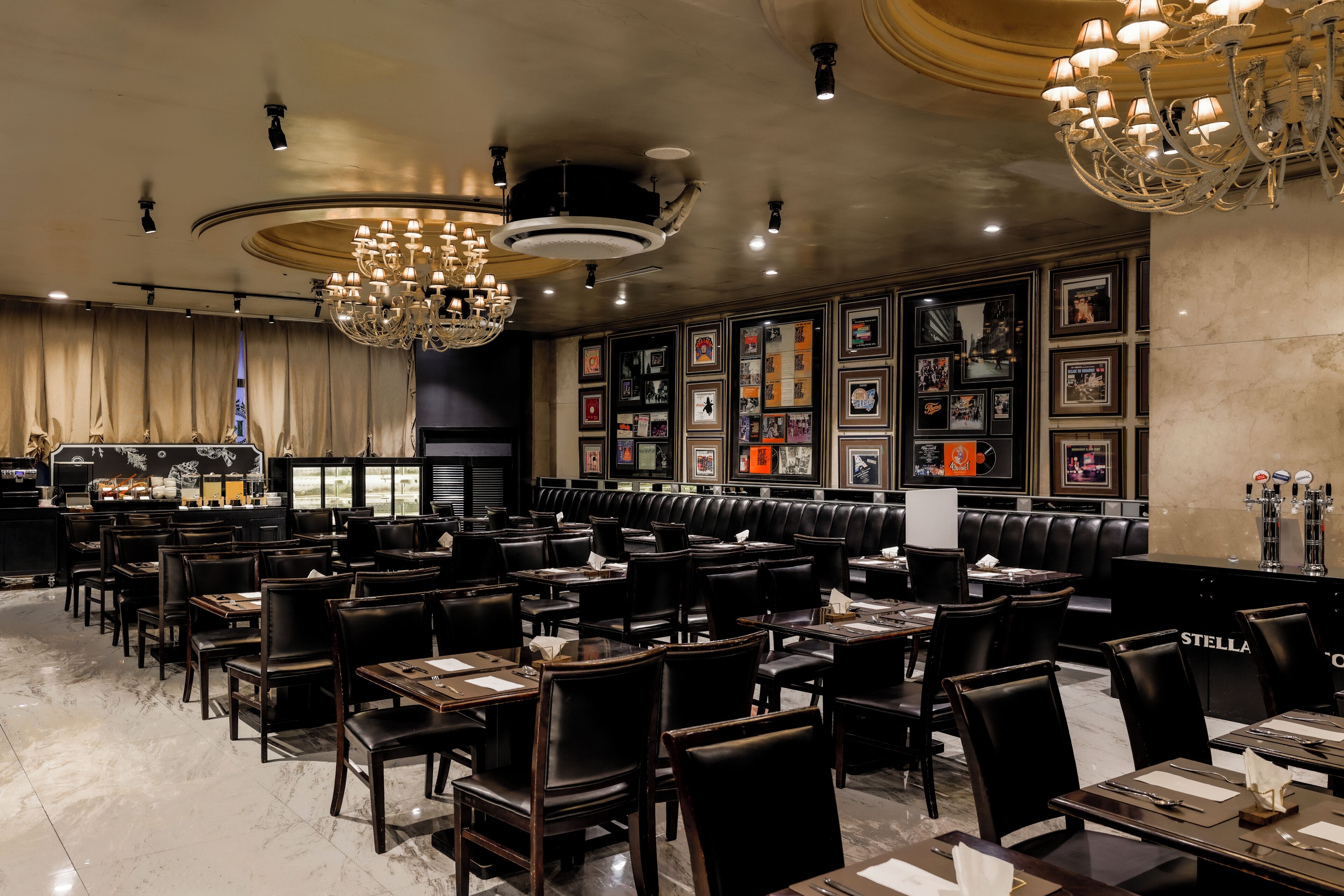 A restaurant with multiple tables and booths, a bar area, and a wall decorated with framed pictures.
