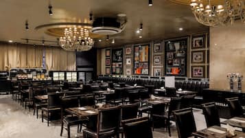 A restaurant with multiple tables and booths, a bar area, and a wall decorated with framed pictures.