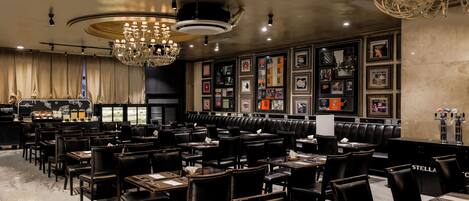 A restaurant with multiple tables and booths, a bar area, and a wall decorated with framed pictures.