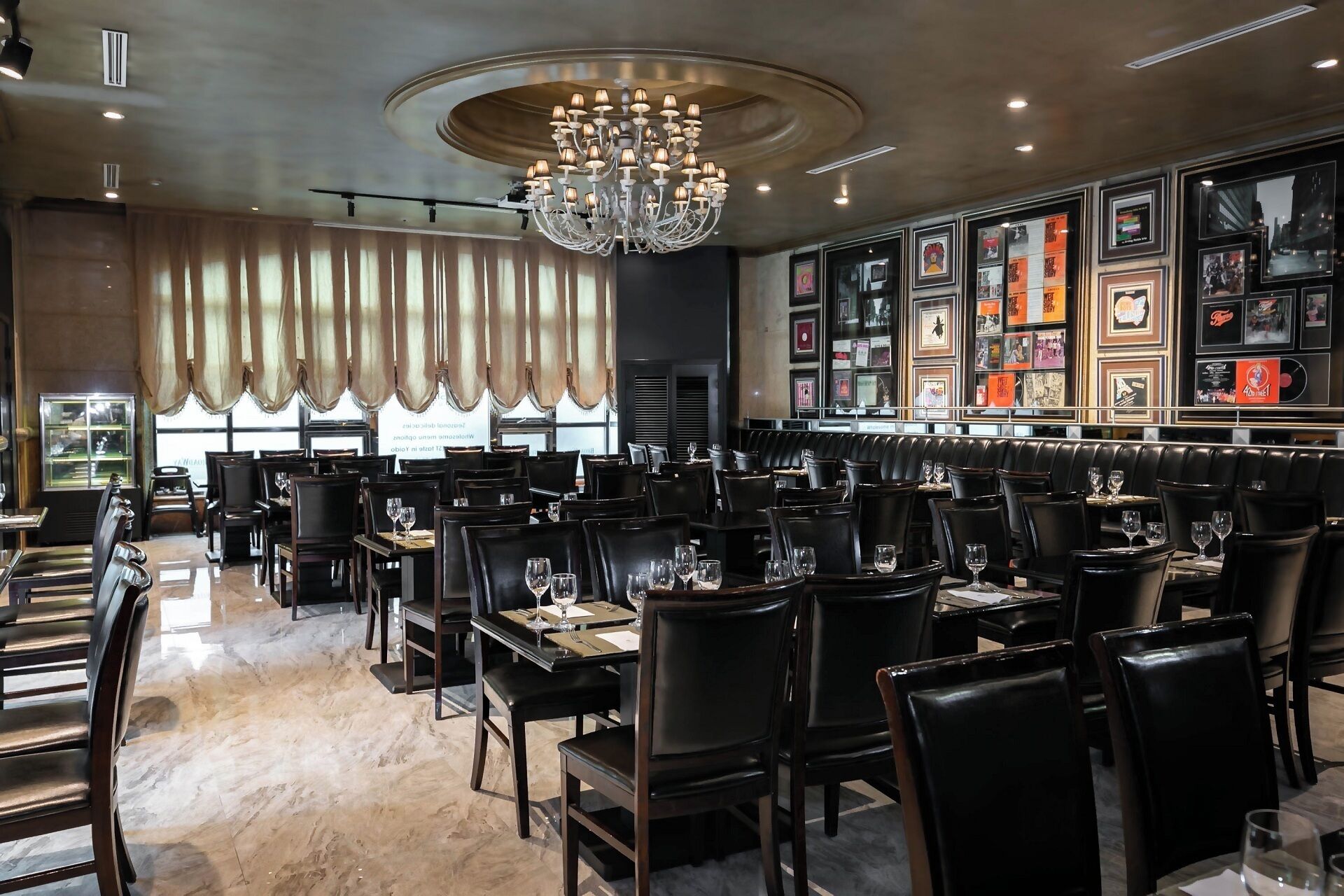 Un restaurante con candelabro, cabinas de cuero negro y cuadros en la pared.