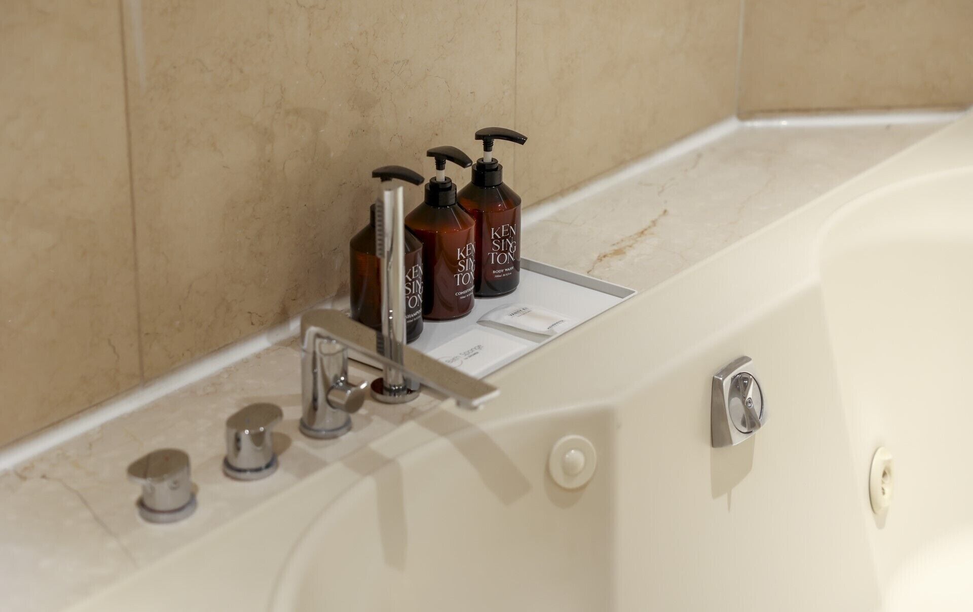 A bathroom with a bathtub, a hand soap dispenser, and a body wash bottle.