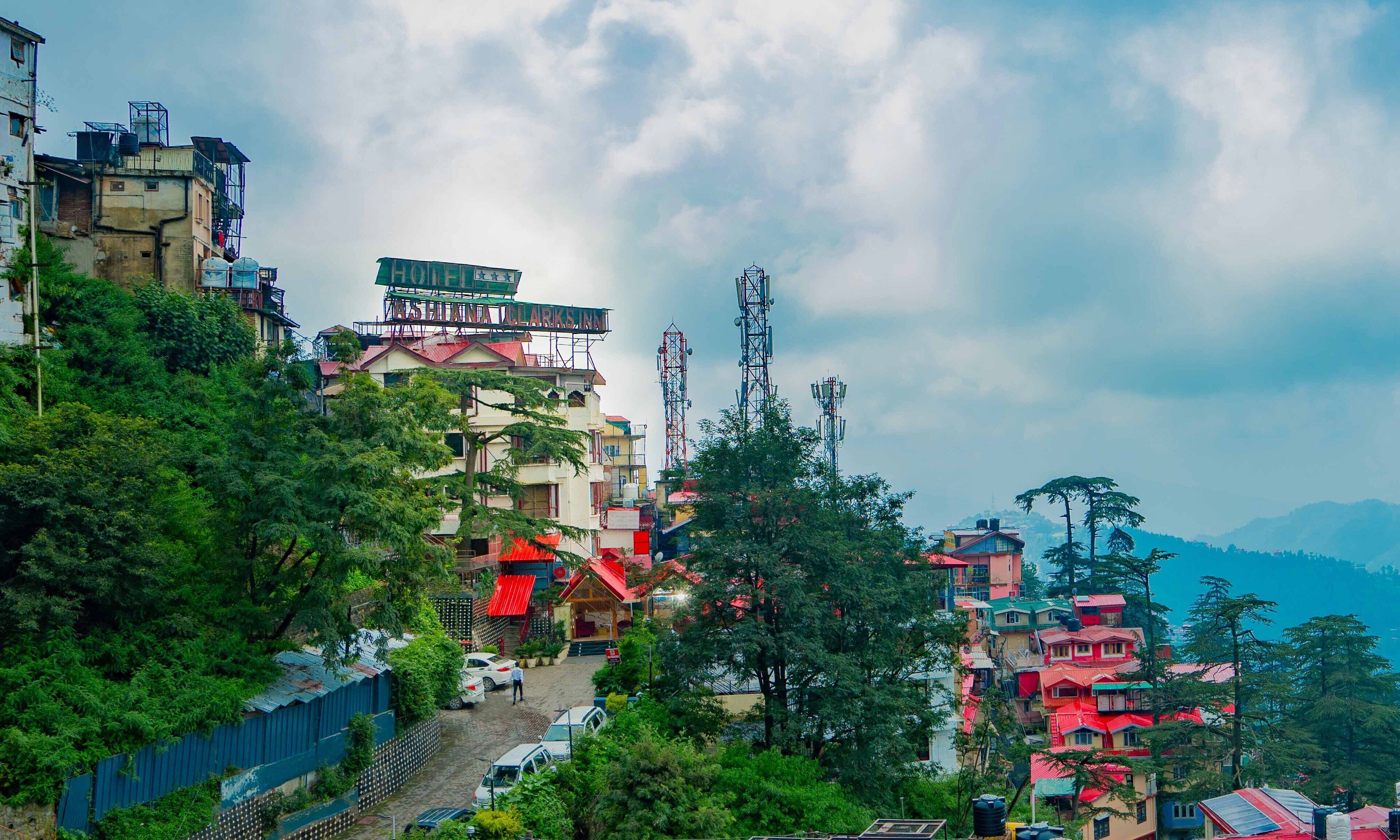 A hotel with multiple floors, a prominent sign, and a view of surrounding buildings and trees.