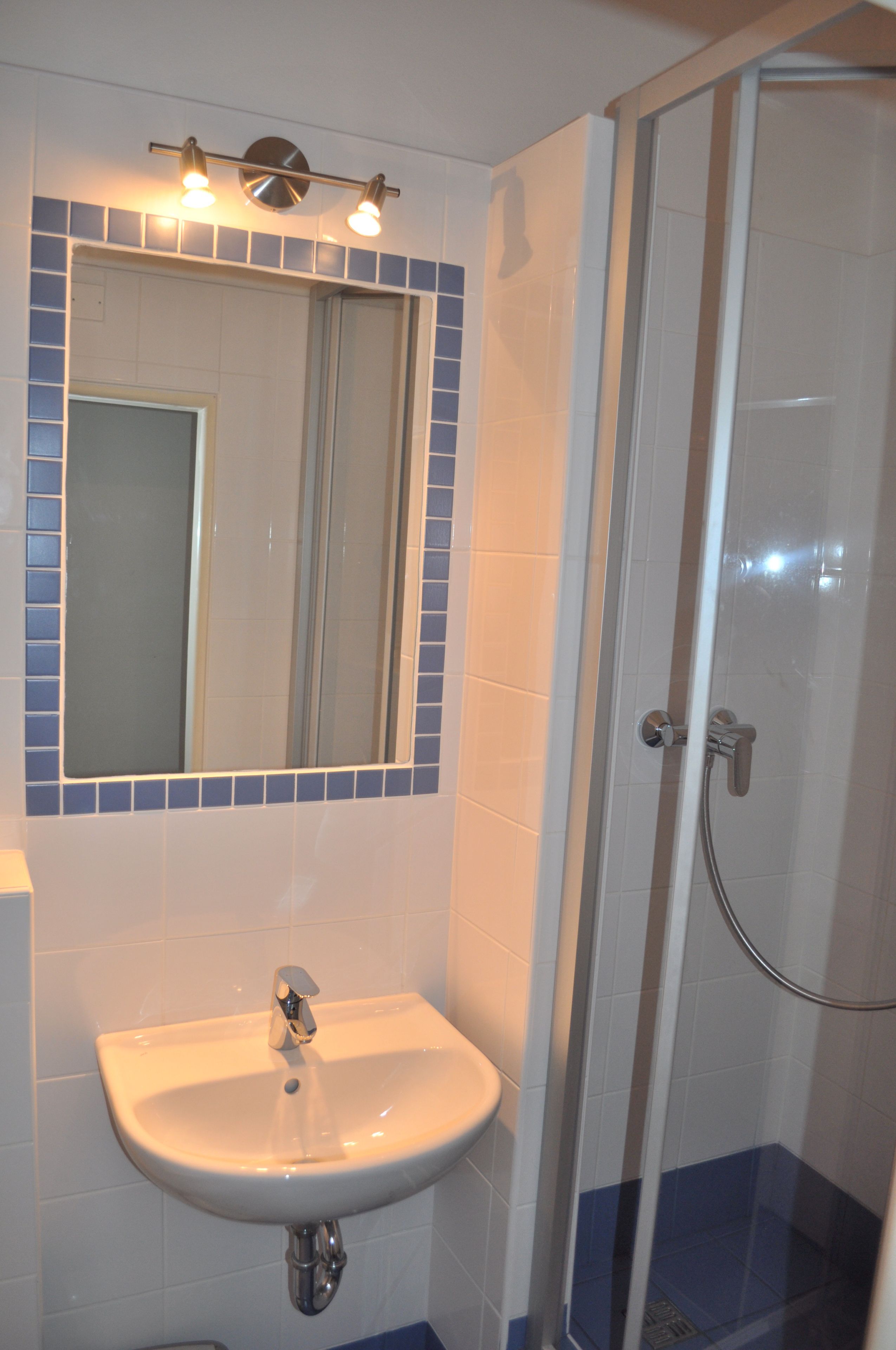 Un baño con lavamanos, espejo y ducha.