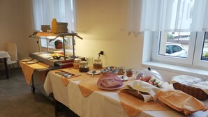 A breakfast buffet setup with a variety of food items, a coffee station, and a window view.