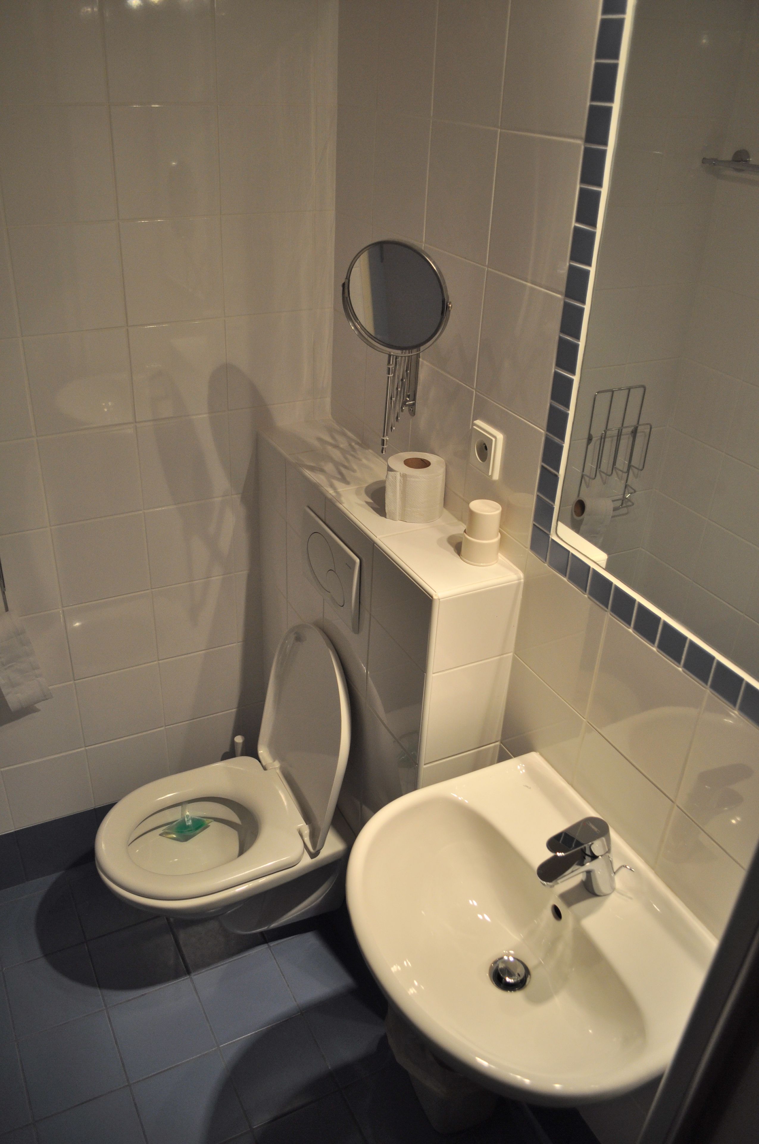A compact bathroom with a toilet, sink, and mirror.