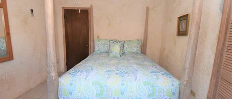 A bedroom with a bed, a wooden door, and a framed picture on the wall.