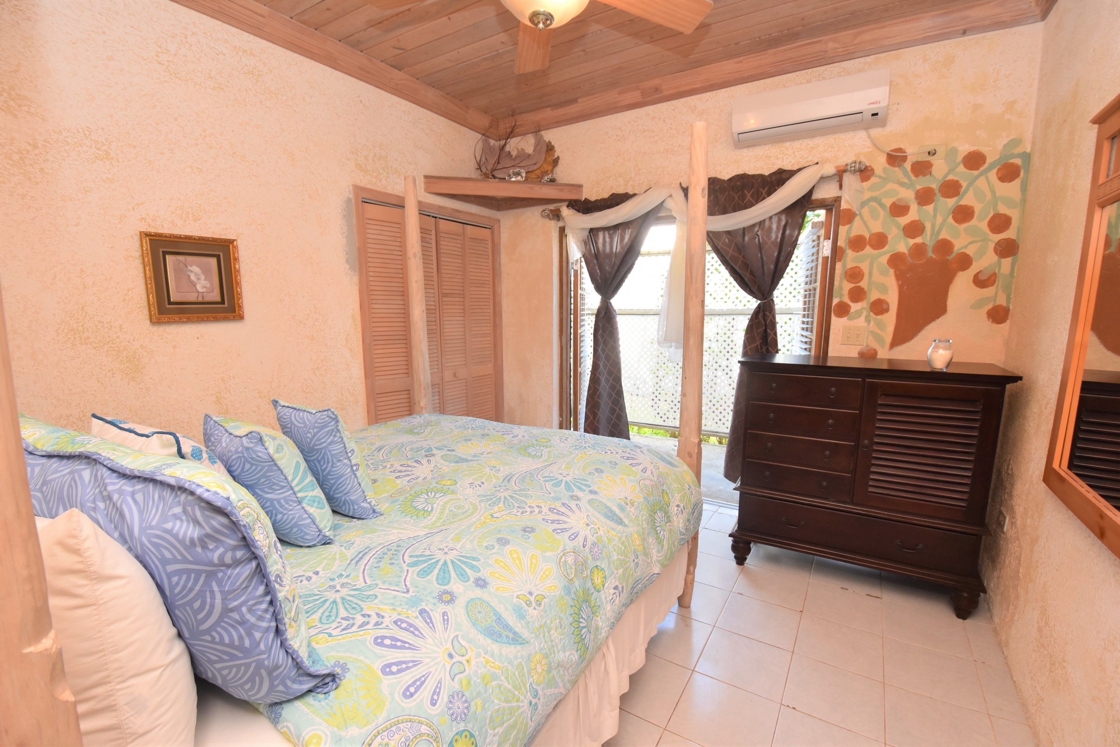 A bedroom with a bed, a dresser, a picture on the wall, and a window with curtains.