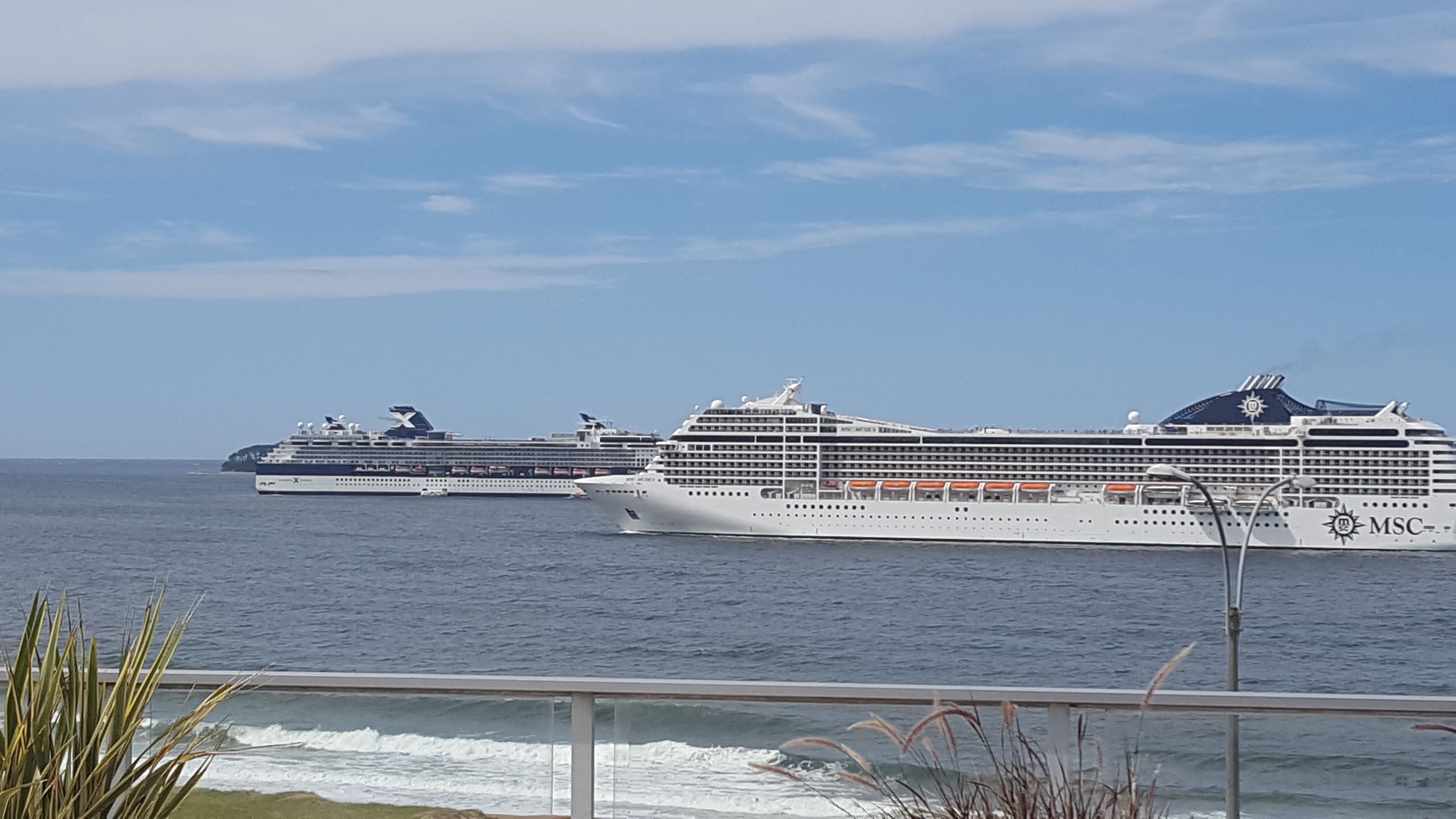 Three cruise ships on the water with a clear sky.
