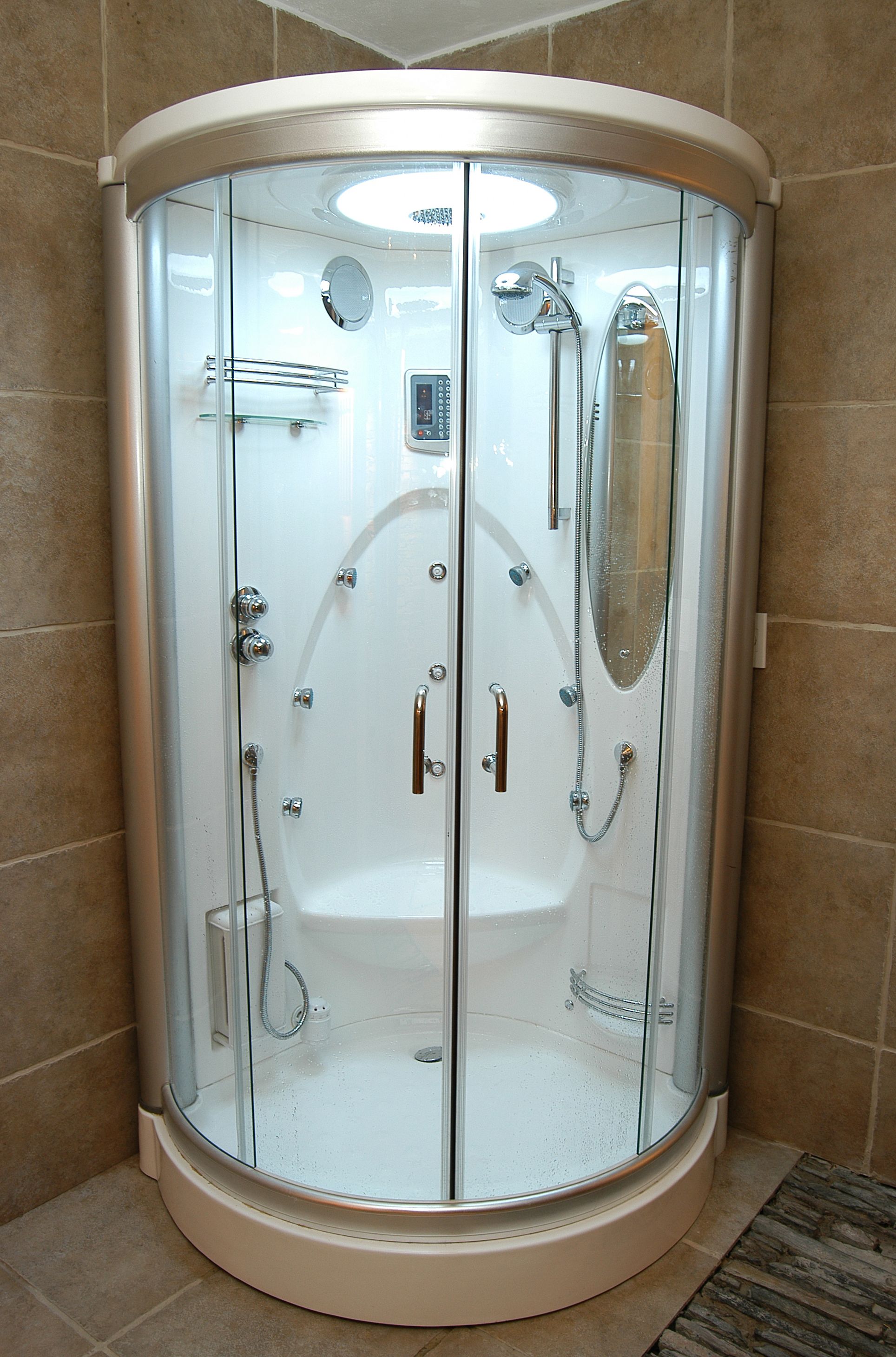Cabina de ducha con paredes de vidrio, cabezal de ducha manual y un asiento integrado.