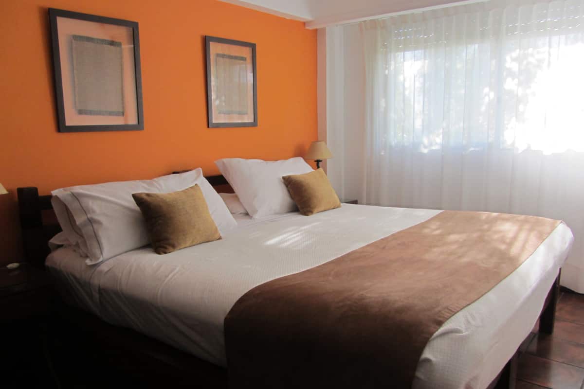 Ein Hotelzimmer mit einem großen Bett, zwei gerahmten Bildern an der Wand und einem fenster mit Vorhängen.