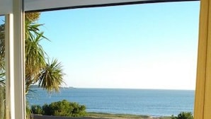 Un balcón con vistas al océano, una silla de lounge y una zona ajardinada.