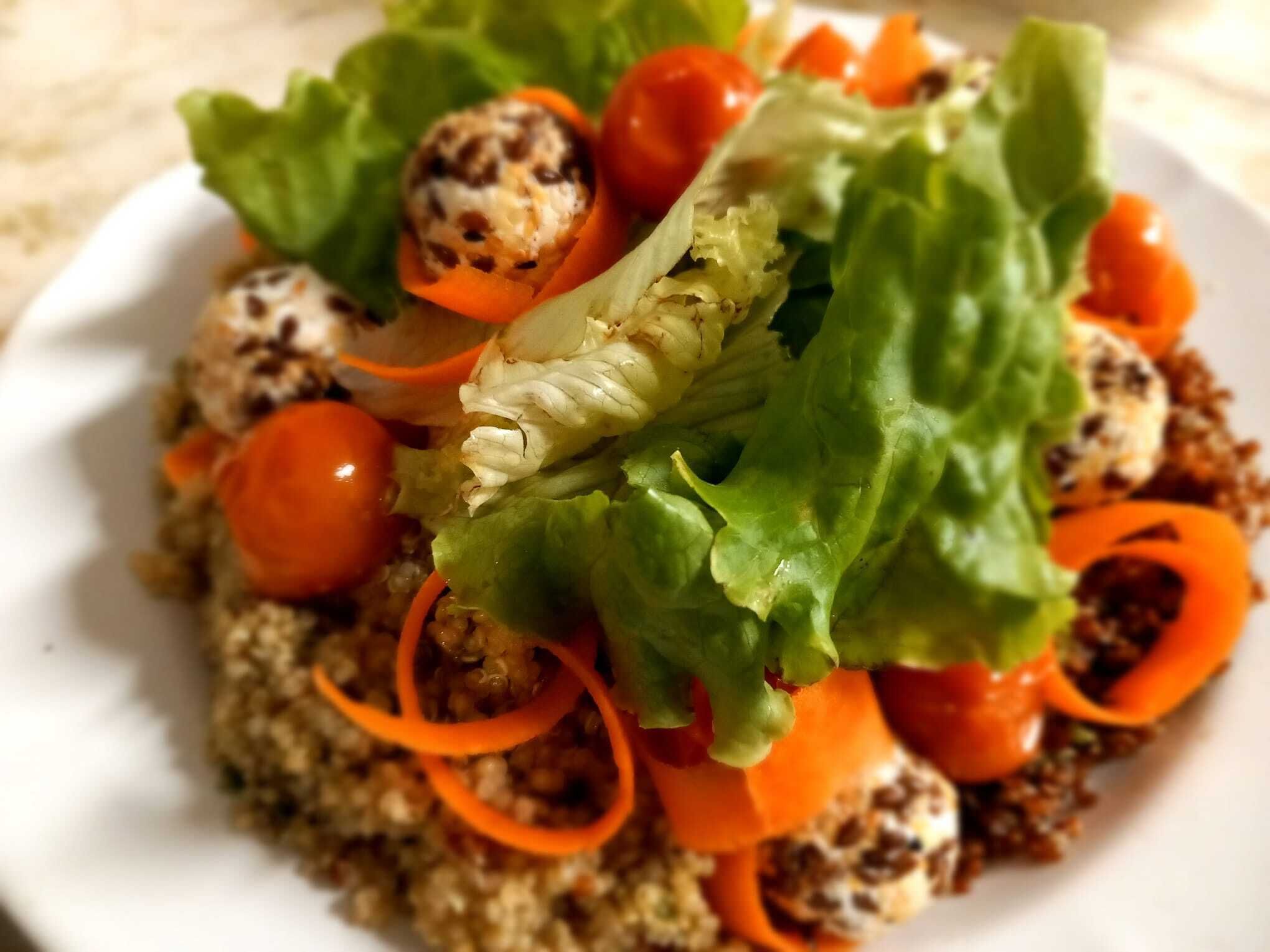 A plate of food with lettuce, cherry tomatoes, and a grain-based dish.