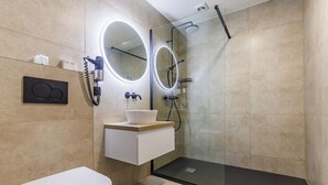 Un baño moderno con inodoro, tocador y zona de ducha con mampara de vidrio.