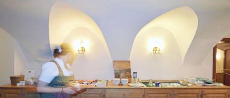 A kitchen with a long counter, equipped with various appliances and utensils, and two wall-mounted light fixtures.