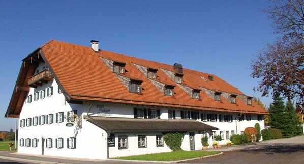 A traditional building with a sloped roof, multiple windows, and a covered entrance area. - Hotel Gasthof Moosleitner (Freilassing)