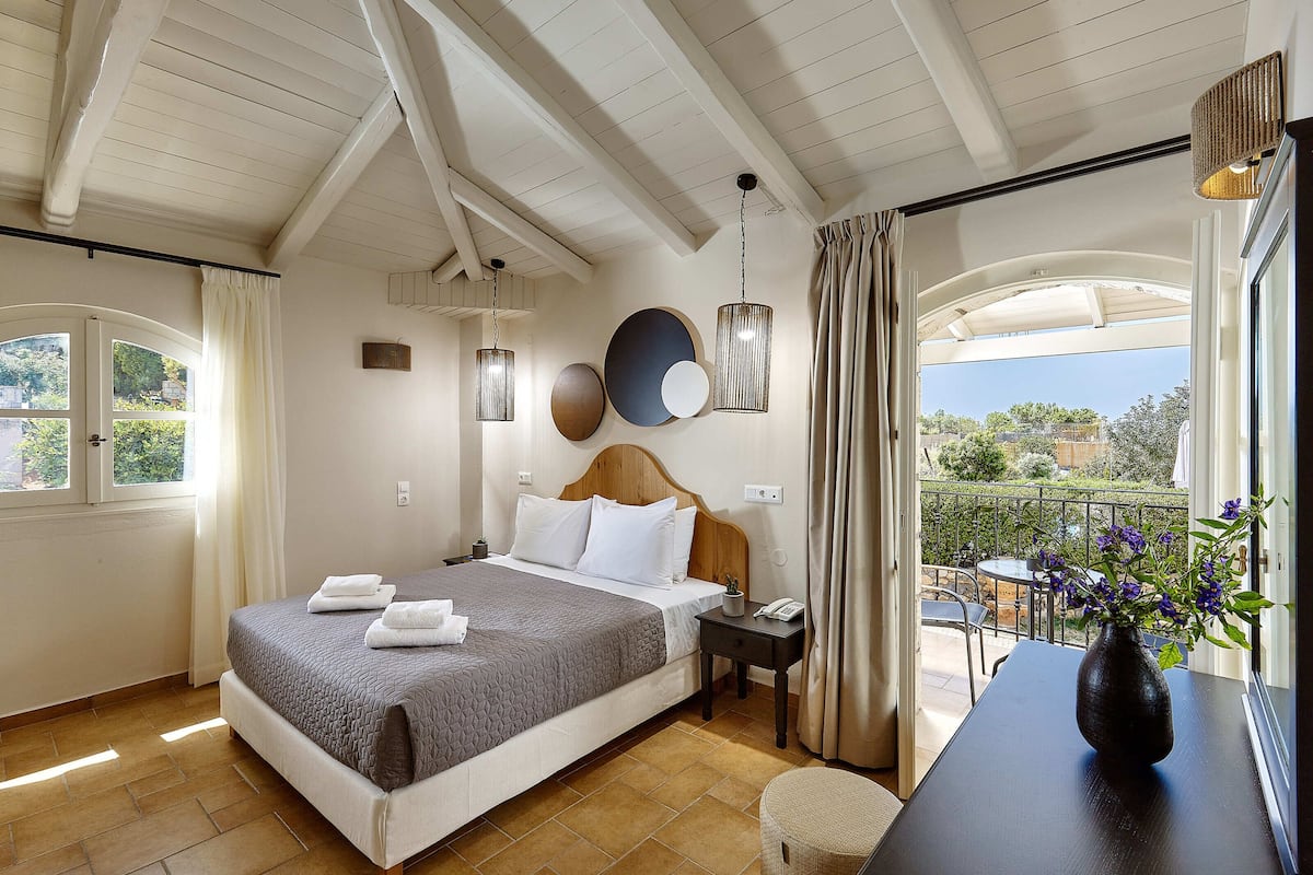 A bedroom with a bed, bedside table, and a view of the outdoors.