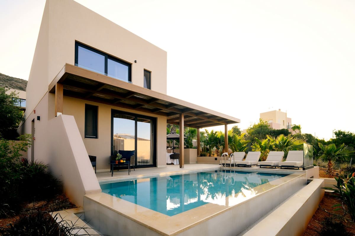 A modern house with a swimming pool, outdoor seating, and a covered patio.