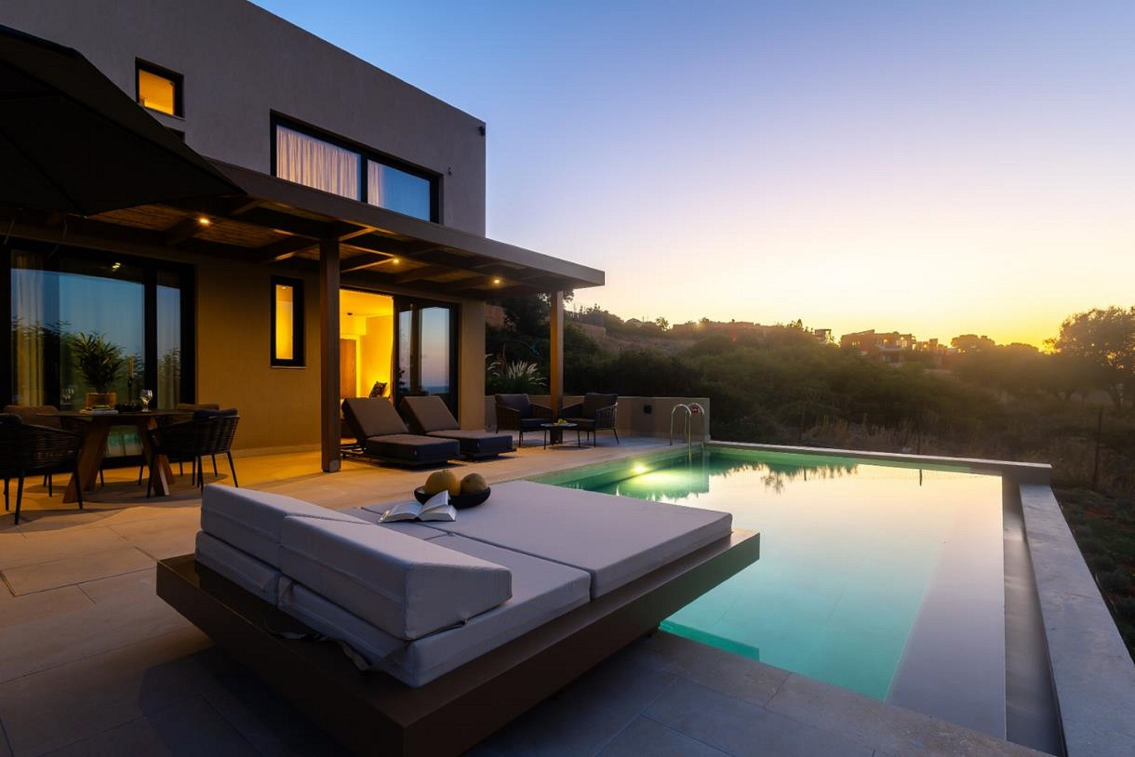 A modern house with a swimming pool, outdoor seating, and a view of the landscape.
