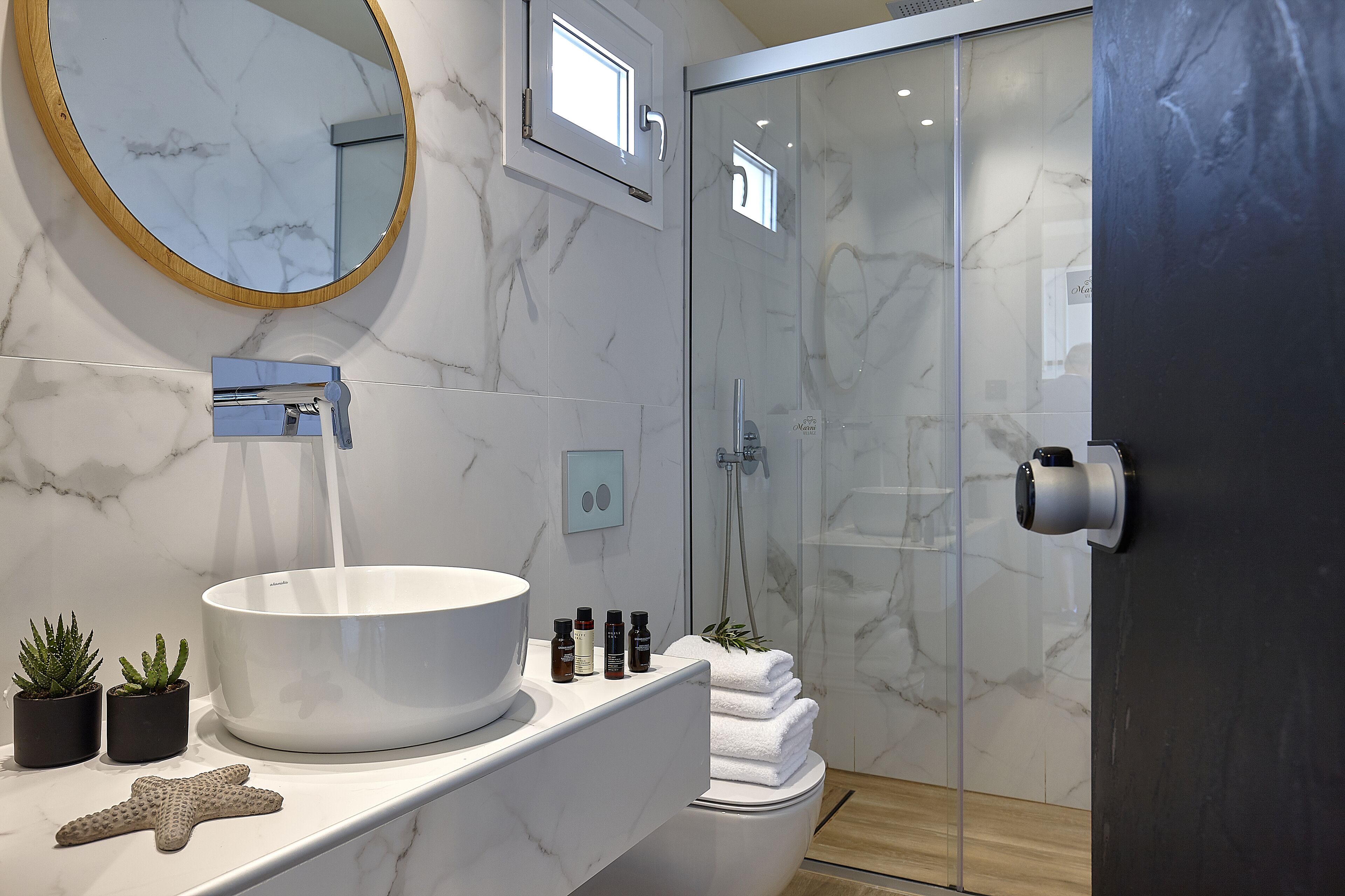 A bathroom with a marble sink, a large mirror, a shower with glass doors, and a towel rack.