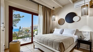 A bedroom with a bed, a bedside table with a phone, a view of the outdoors, and a window with curtains. - Marni Village (Hersonissos)