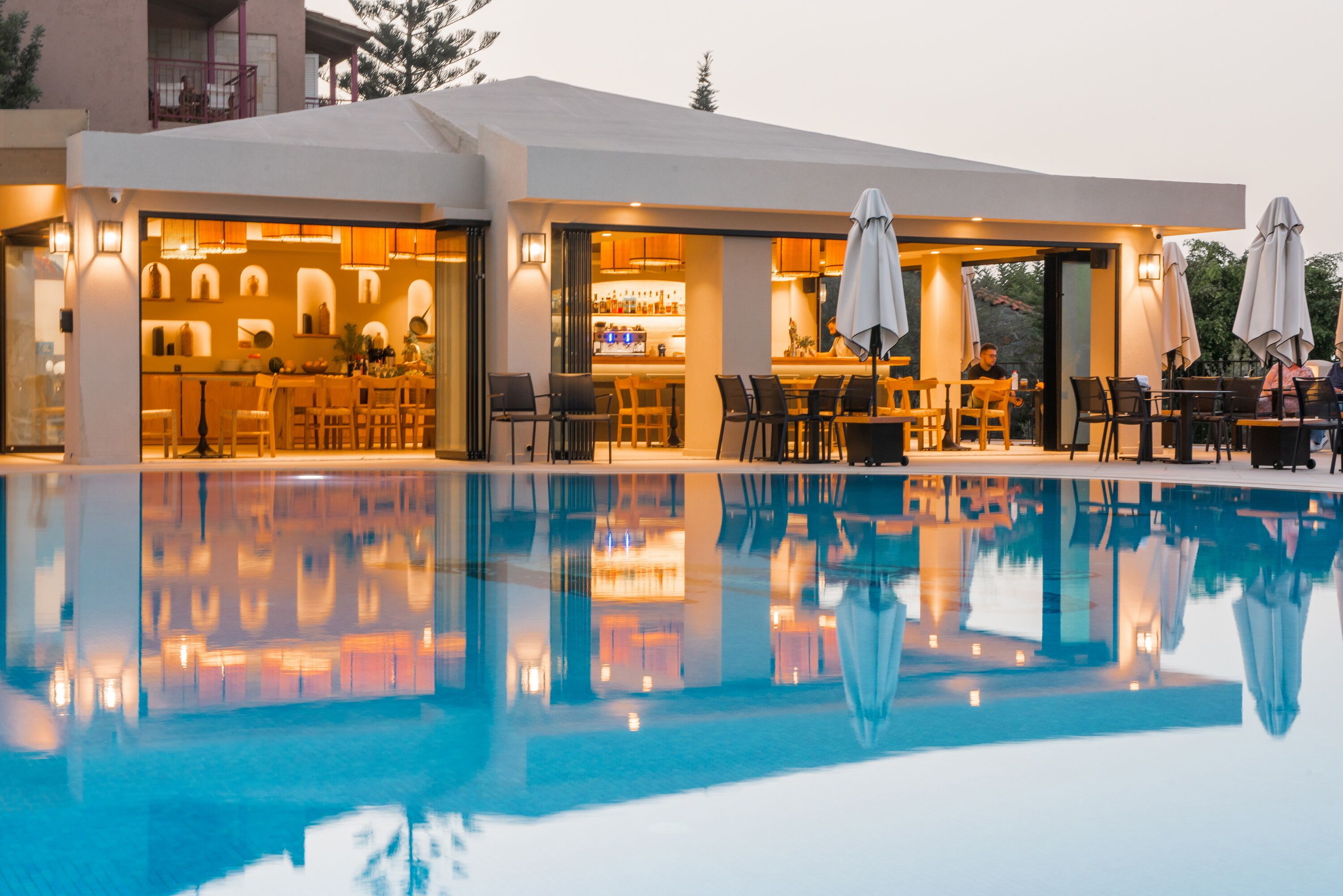 A modern hotel with an outdoor pool, bar area, and dining space.