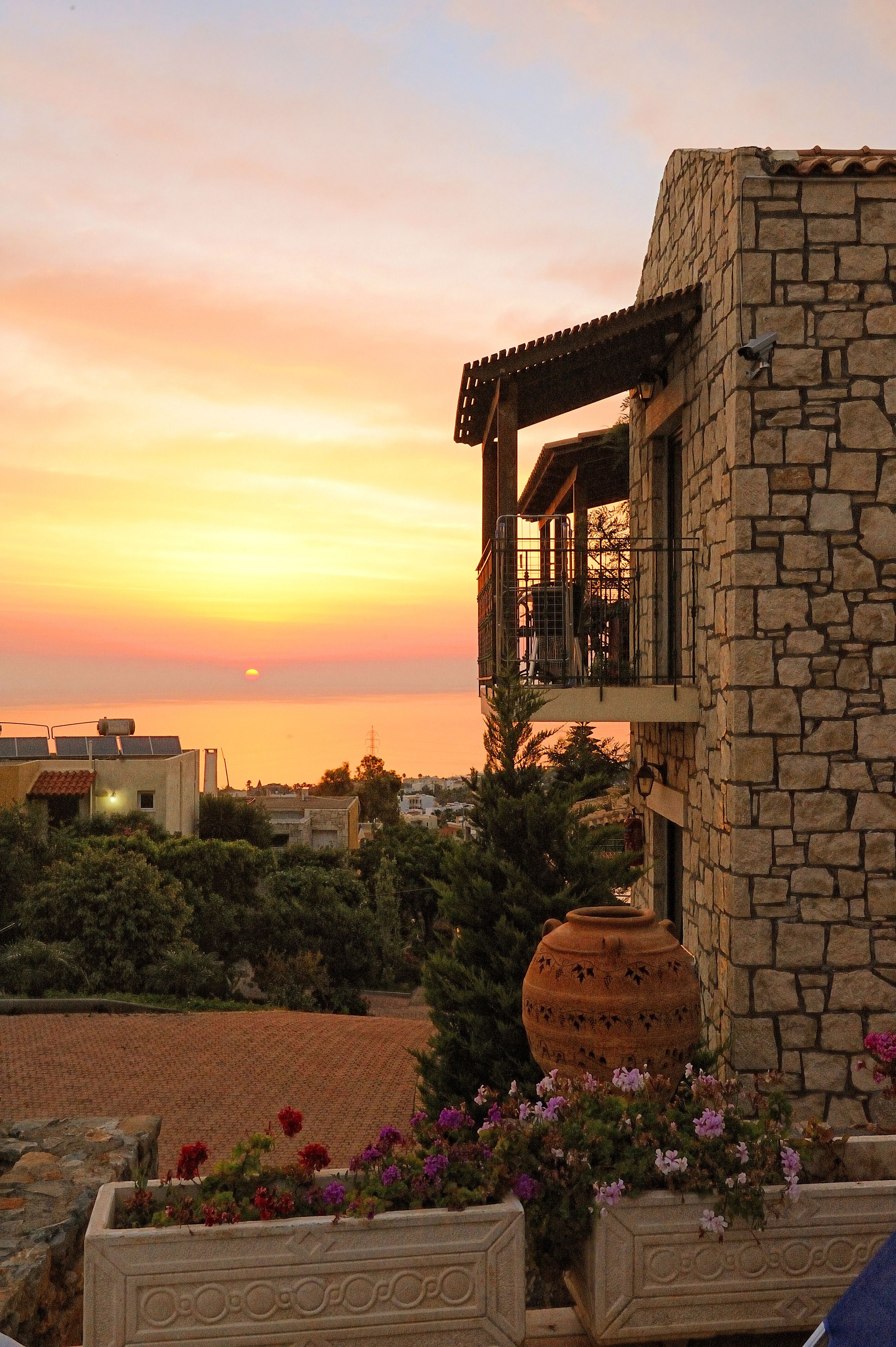 Ein Steinhaus mit Balkon mit Blick auf einen Sonnenuntergang.