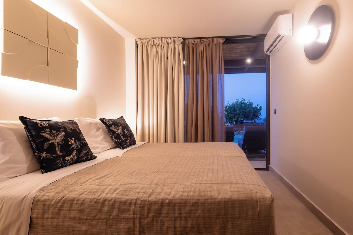 A hotel room with a large bed, beige curtains, and a view of the outdoors.
