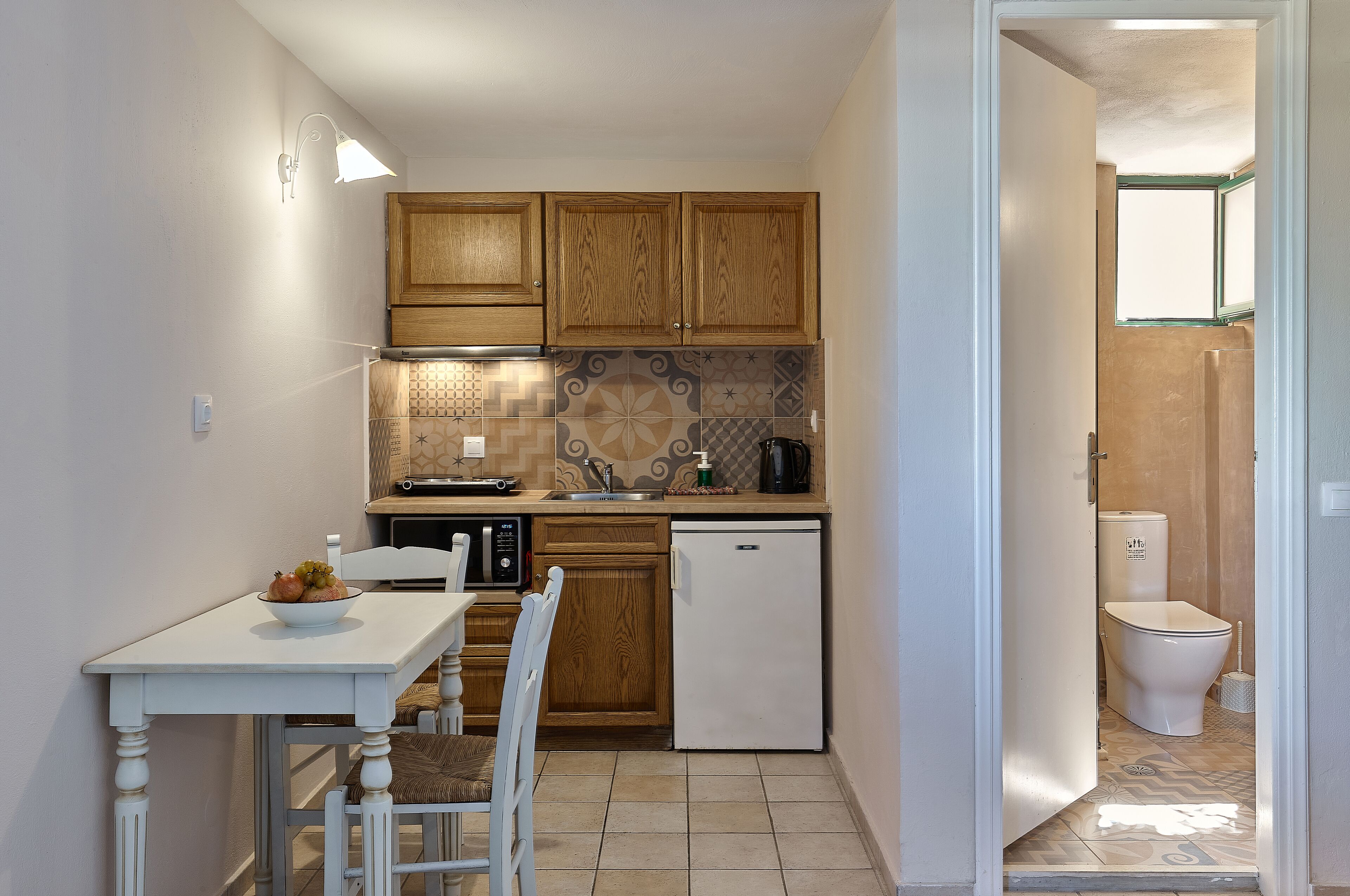 A compact kitchen with wooden cabinets, a white refrigerator, a microwave, and a sink.