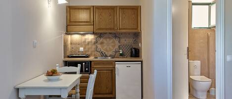 A compact kitchen with wooden cabinets, a white refrigerator, a microwave, and a sink.