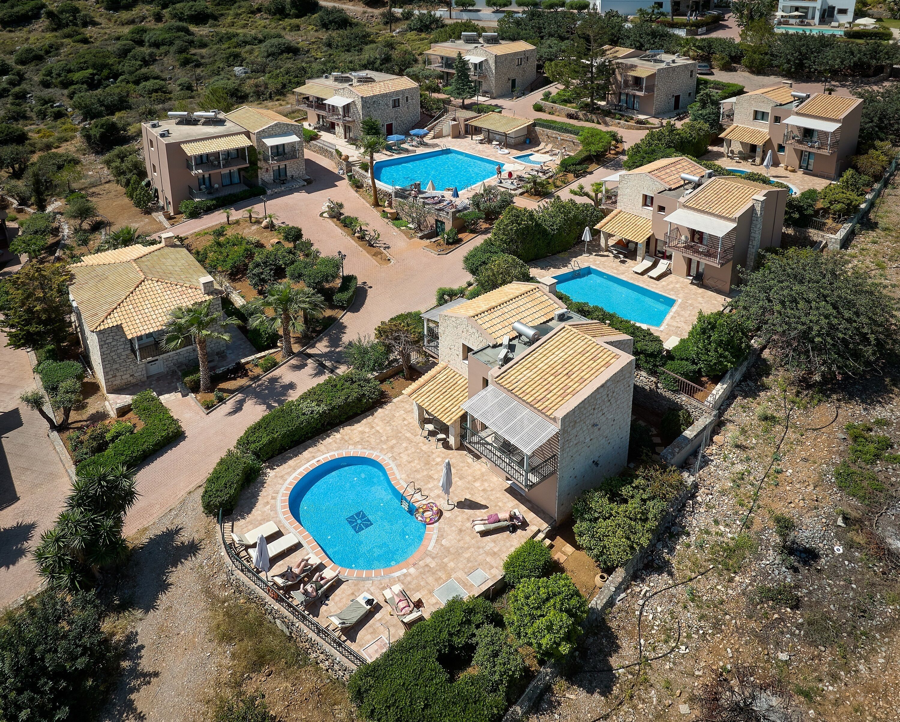 An aerial view of a resort with multiple buildings, swimming pools, and landscaped areas.