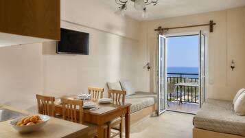 Eine moderne Küche mit Essbereich, einer Couch und einem Balkon mit Meerblick.