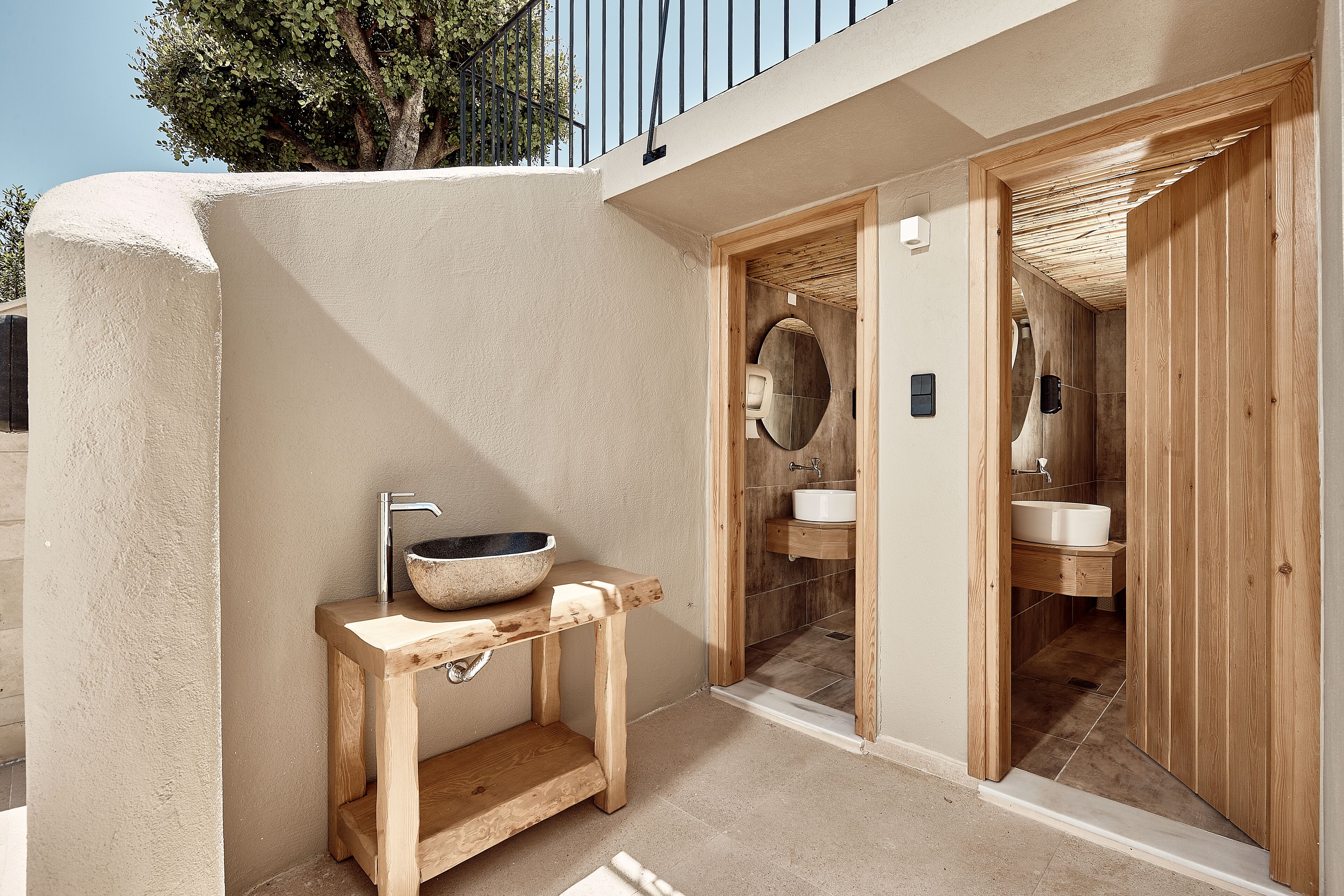 A modern bathroom with a wooden vanity, a large bowl sink, and a glass-enclosed shower area.