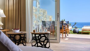 A modern room with a view of the sea, featuring a round table with a bowl of fruit, a lamp, and a glass of water. - Marni Village (Hersonissos)