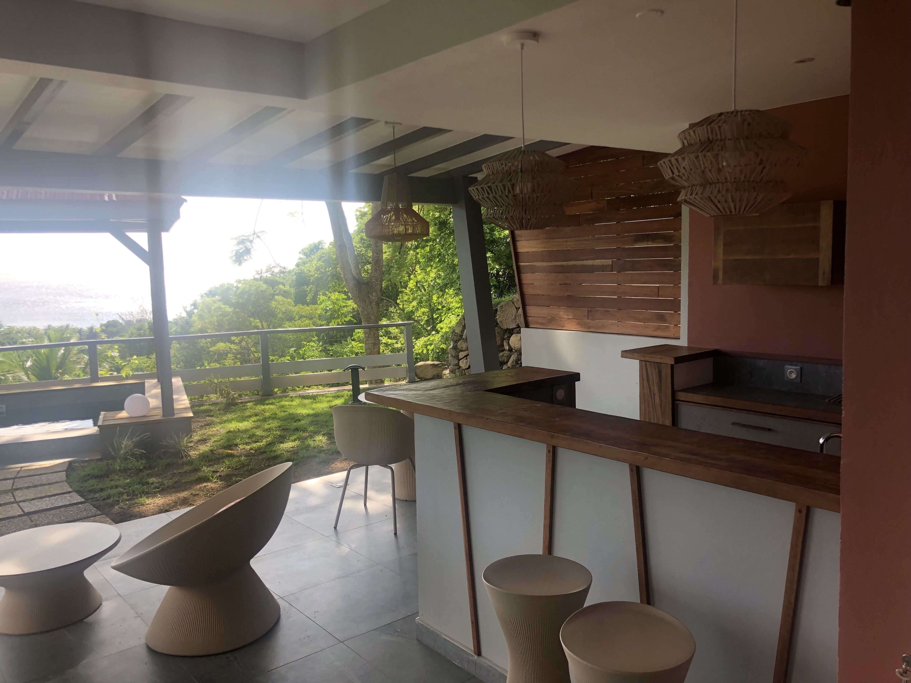 A modern kitchen with a bar area, a dining table, and a view of the outdoors.