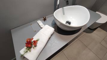 Een moderne badkamer met een groot wit wastafel, een handdoek en decoratieve bloemen.