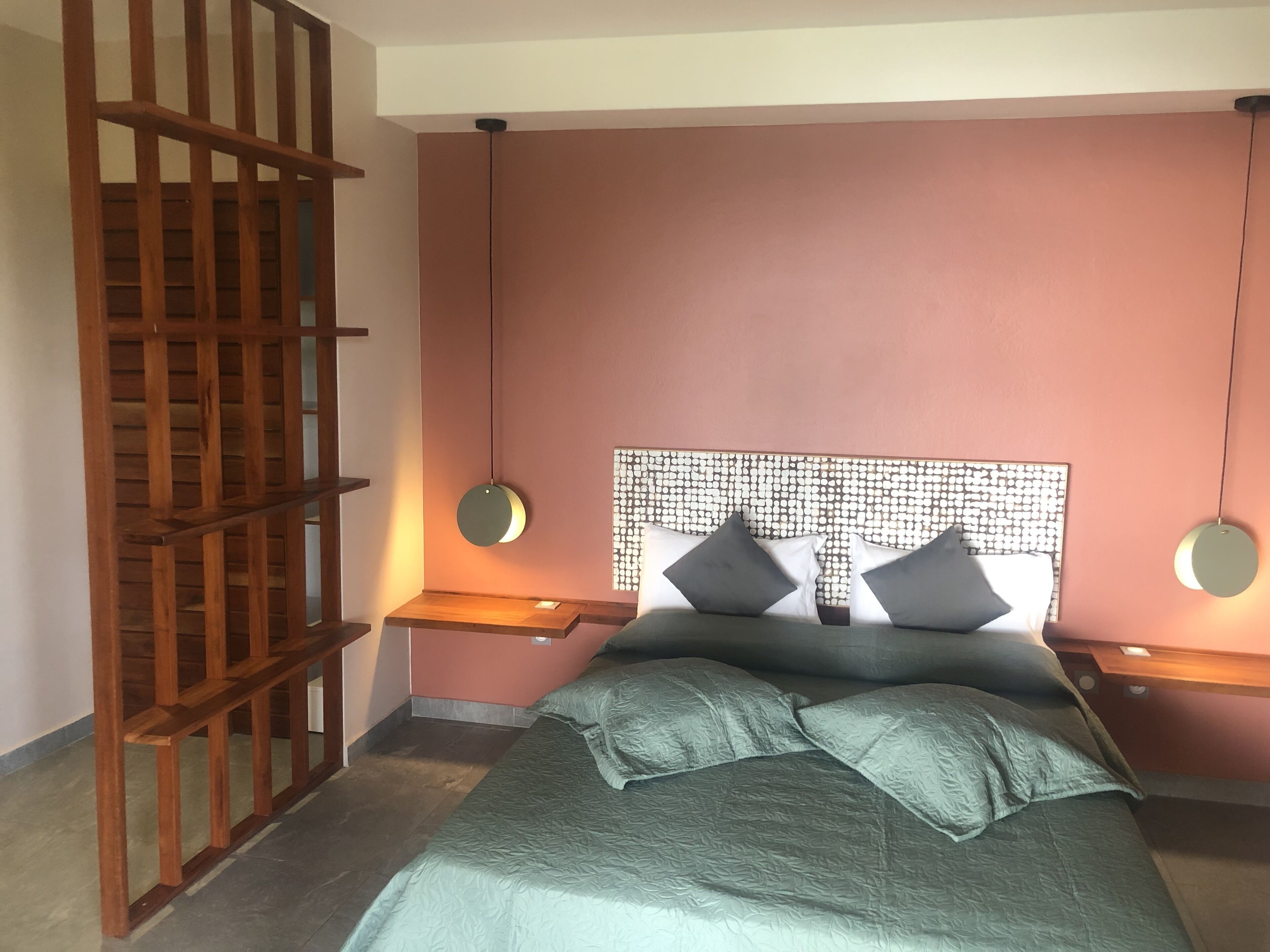 A bedroom with a bed, two bedside tables, a wooden ladder, and a patterned headboard.